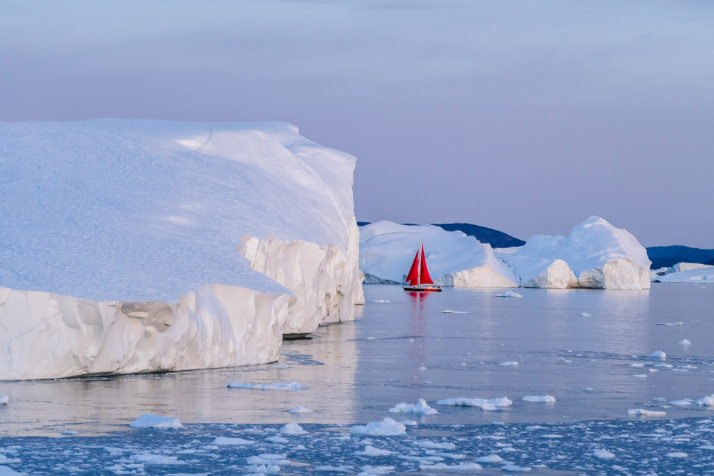 Small red sailboat dwarfed by massive icebergs, illustrating that AI sees only the visible portion of disability appeals